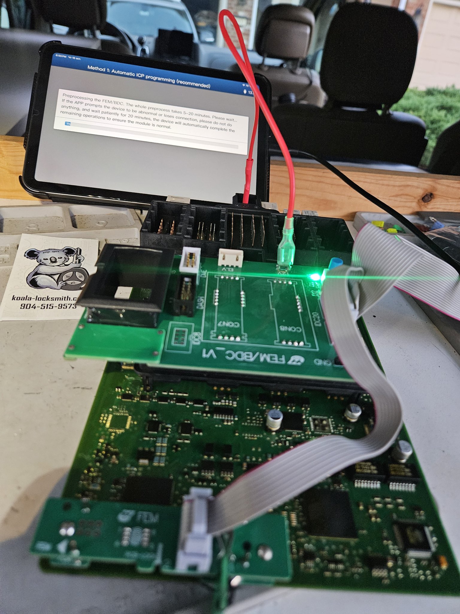 BMW module connected to programming equipment beside a tablet in the mobile work area